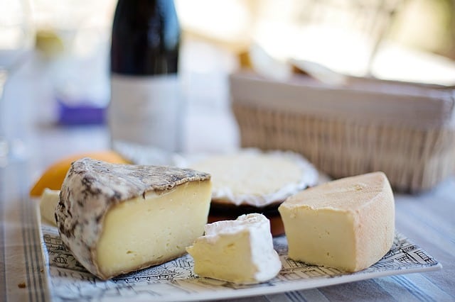 Tábua com queijos e vinho ao fundo