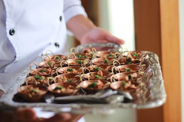 Entrada sofisticada Chef segurando bandeja com pequenas porções de comida