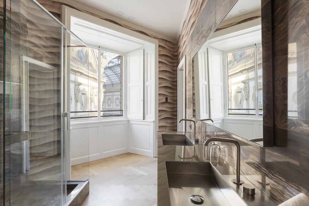 duas pias e a casa de banho do hotel Galleria Vik Milano, que tem uma janela com vista para a Galleria Vittorio Emanuele II