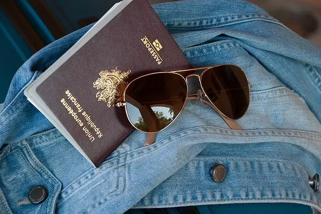 passaporte francês e óculos sobre blusa jeans
