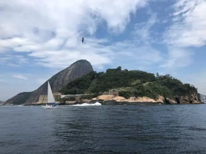 Montanha, veleiro em alto mar e pássaros