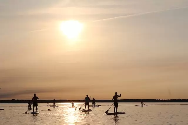 Praticantes de stand up paddle e o pôr do sol
